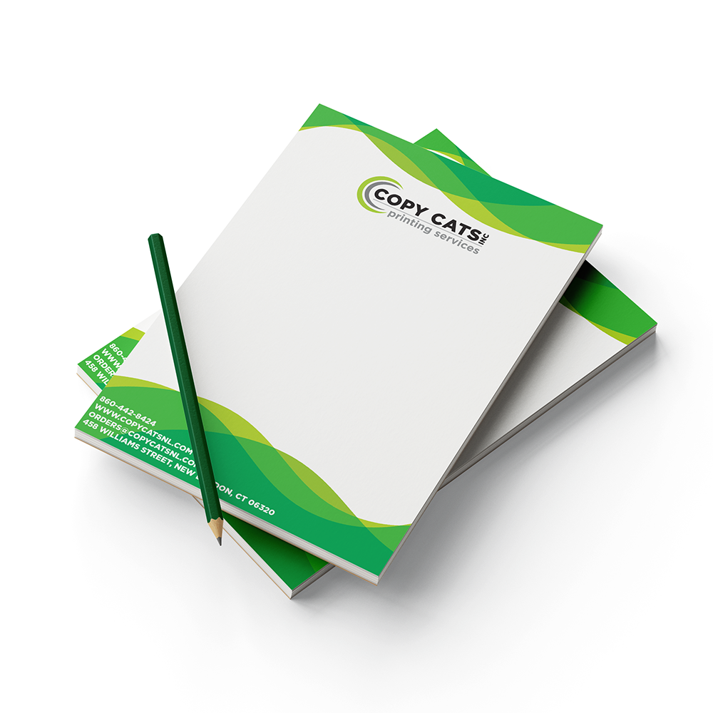 Two notepads on top of one another with a pencil.